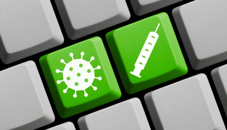 Coronavirus Symbol und Spritze auf grüner Computer Tastatur