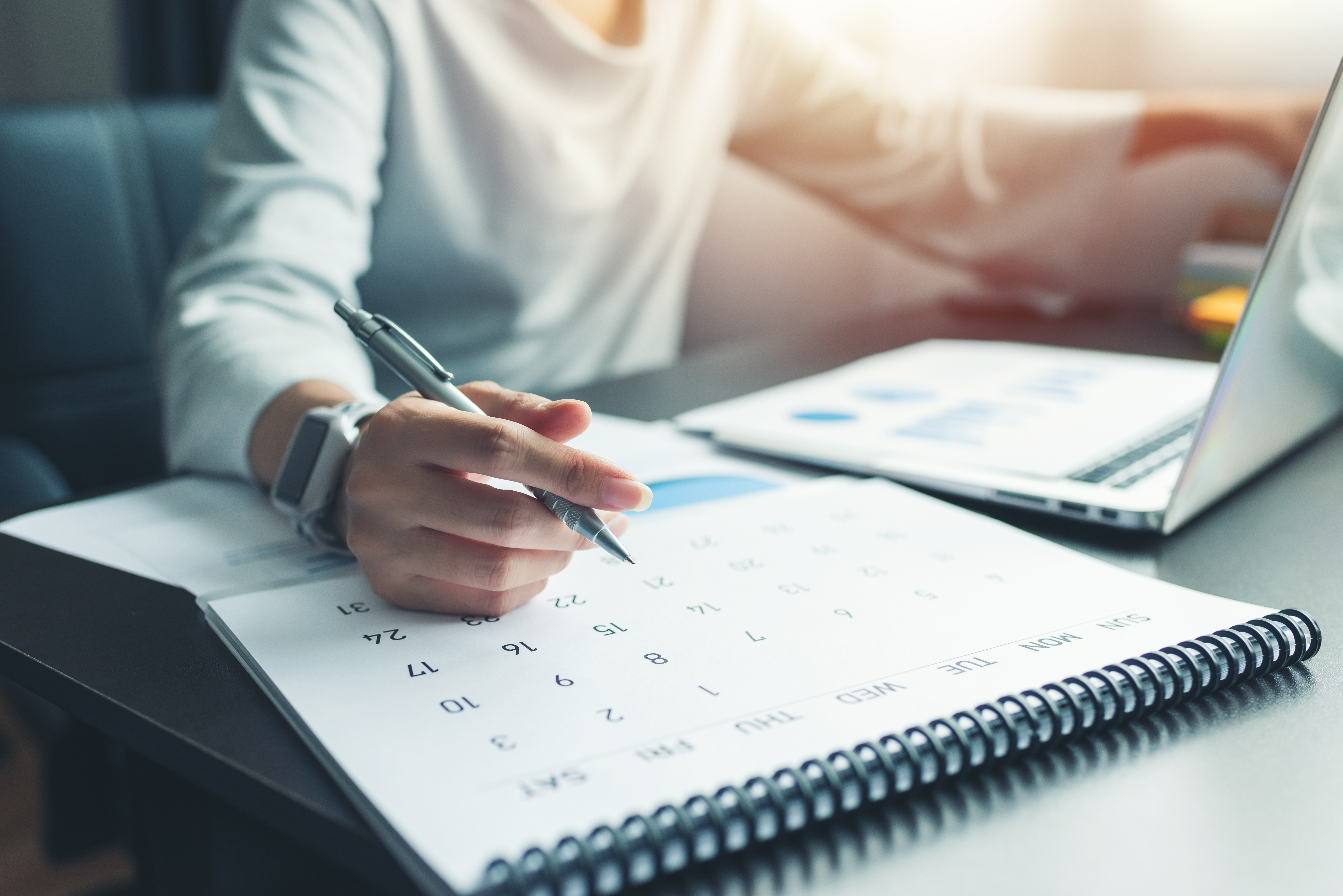 Business woman sitting working and thinking to plan event with calendar and laptop